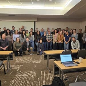 A group of training participants stand in front of a white board.