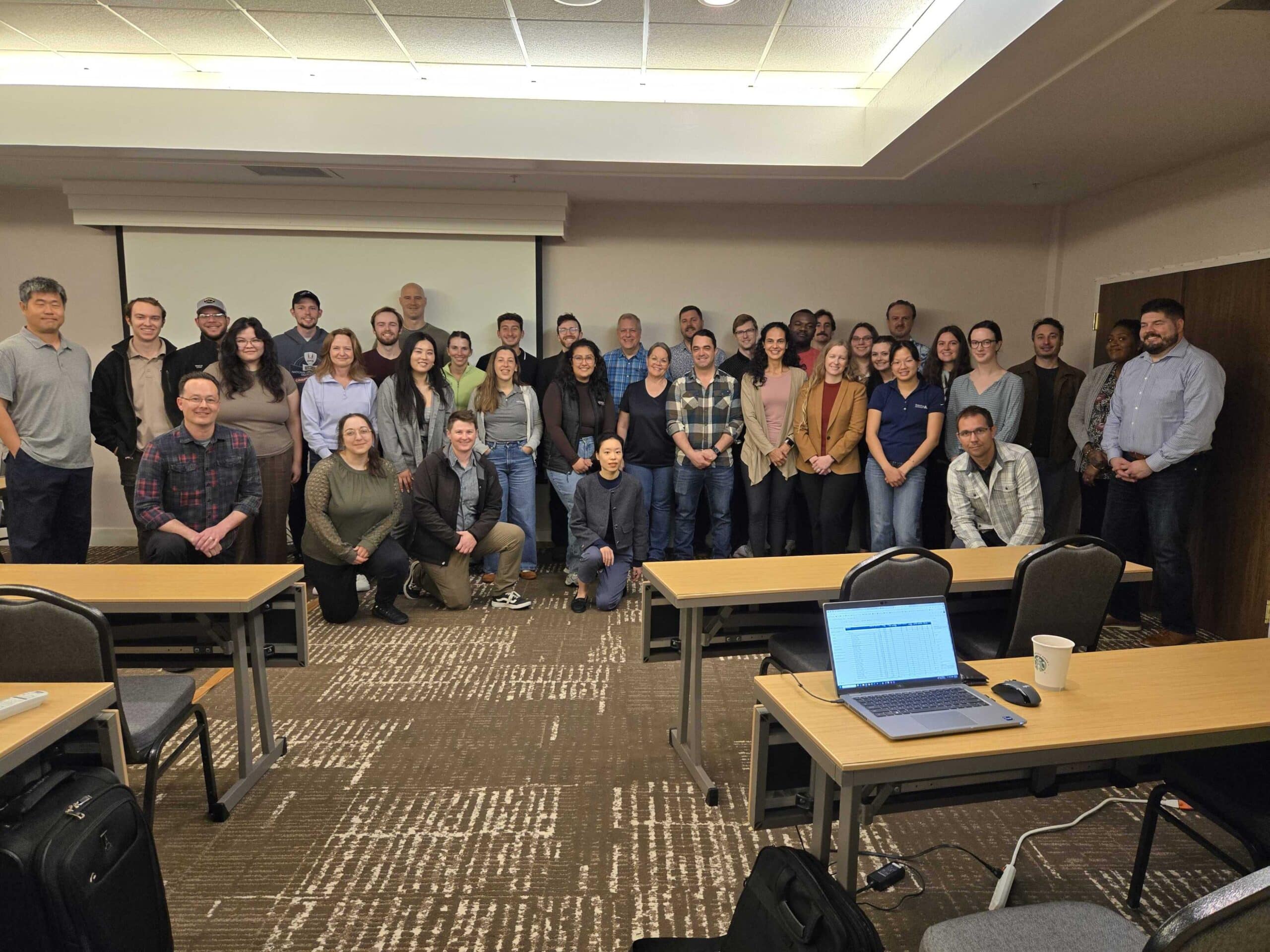 A group of training participants stand in front of a white board.