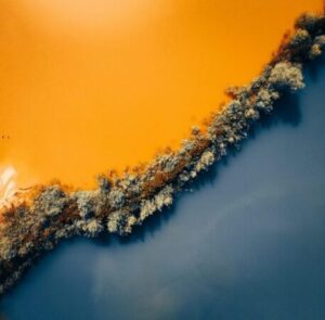 Contrasting orange and blue water is separated by a line of trees going diagonally across the image.