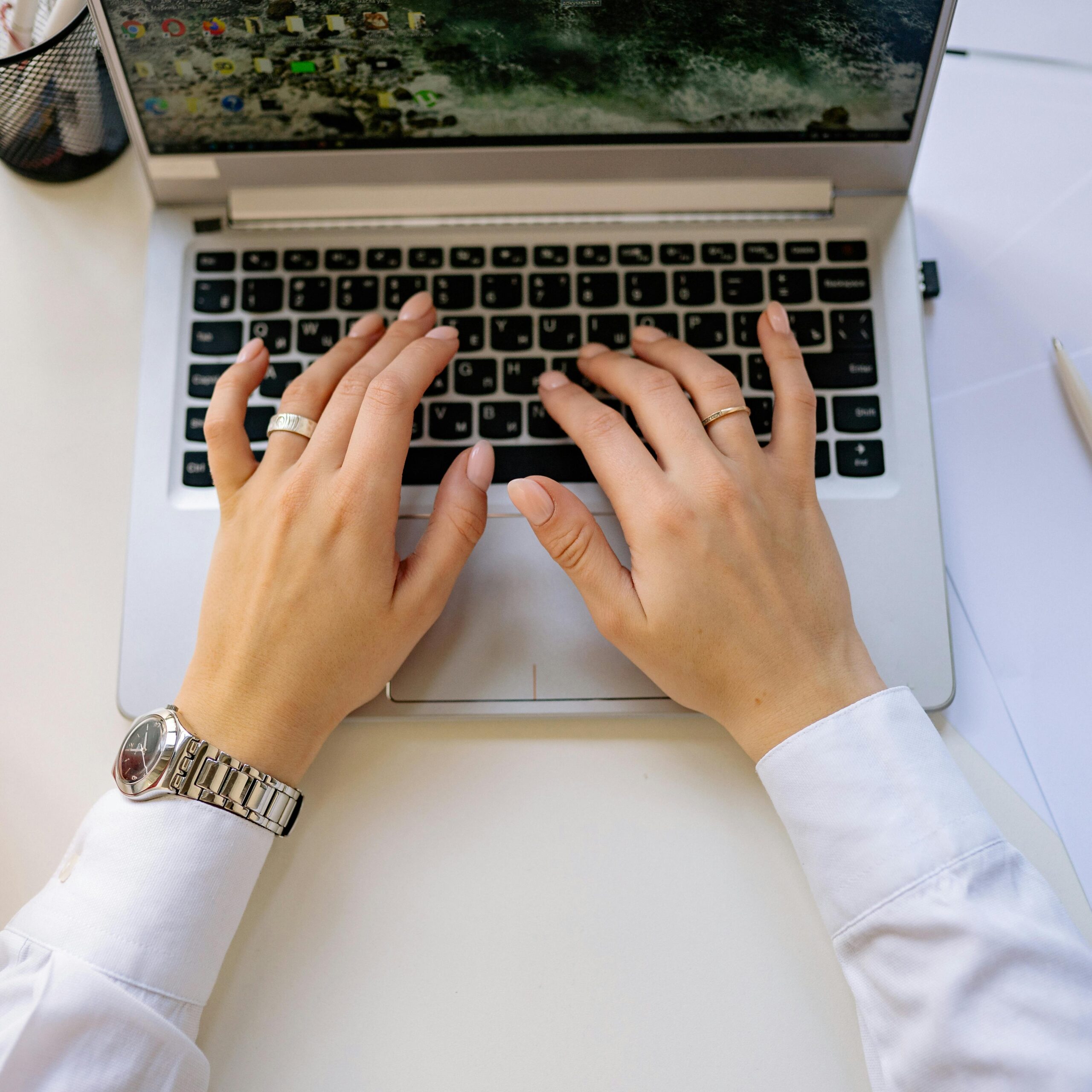 A person's hands hover over a laptop keyboard as they type.