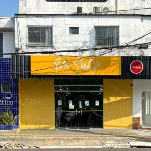 The front of a cafe with a sign above and yellow-painted walls.